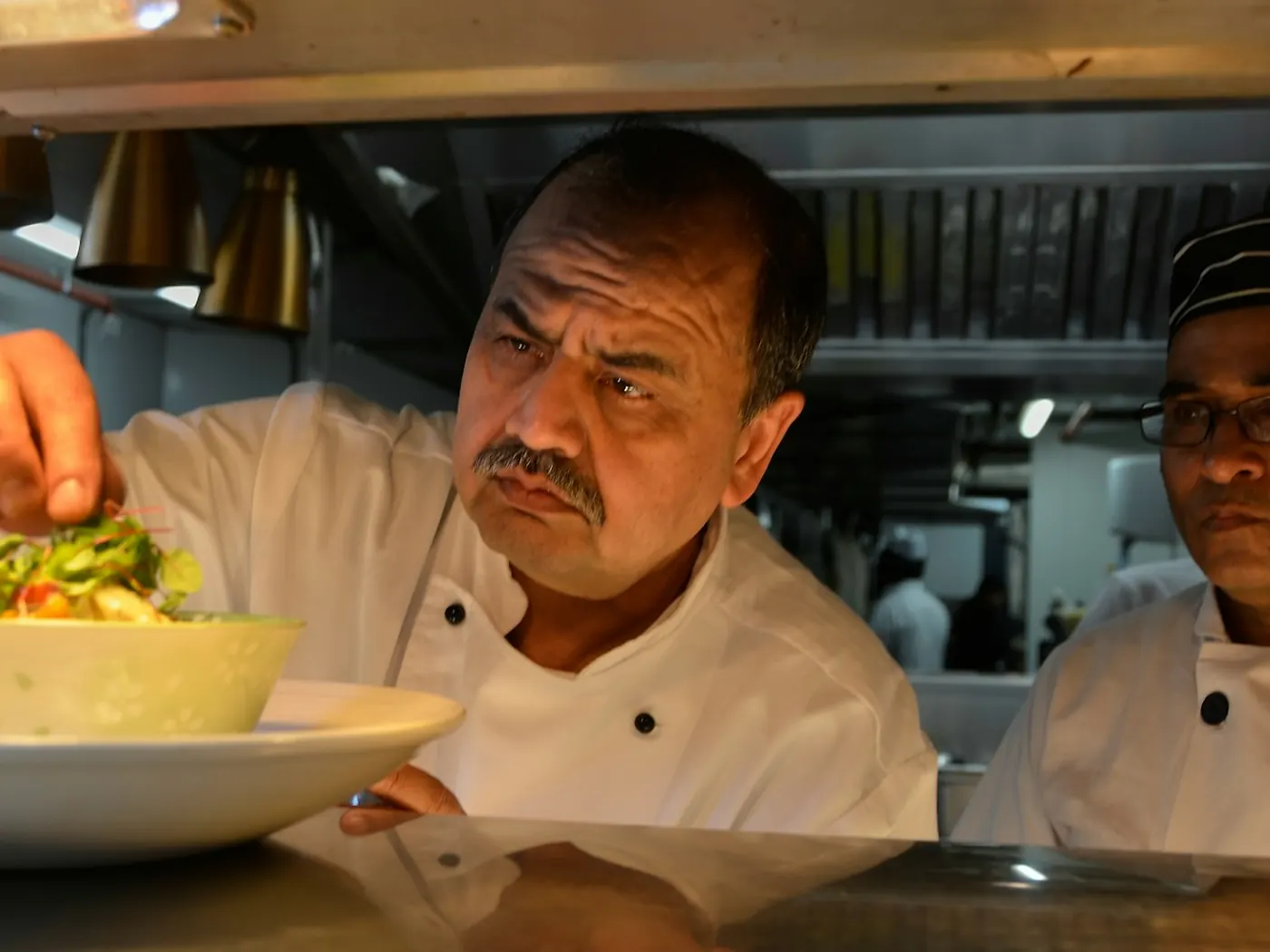 Chef che rifinisce un piatto al pass della cucina