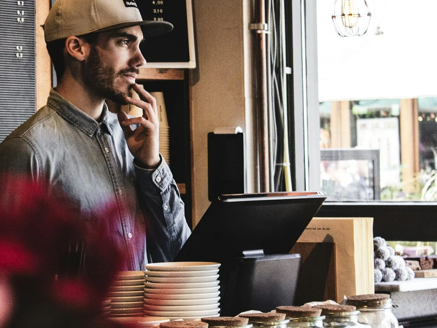 Cassiere al banco di un caffè accanto al monitor di cassa
