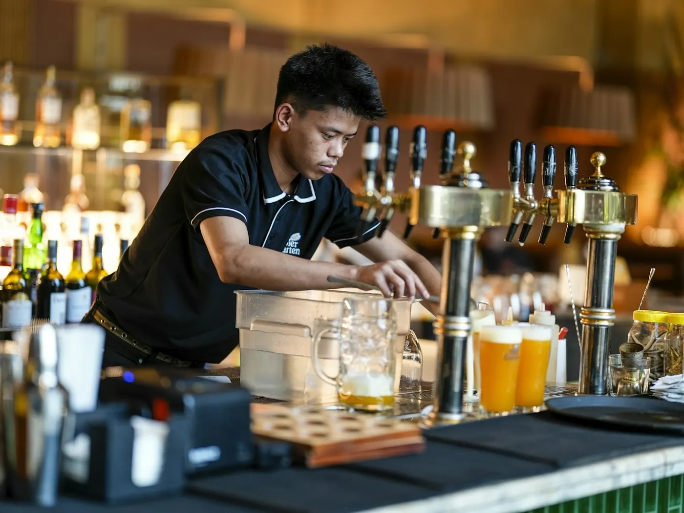 Barista che prepara le birre alle spine del banco