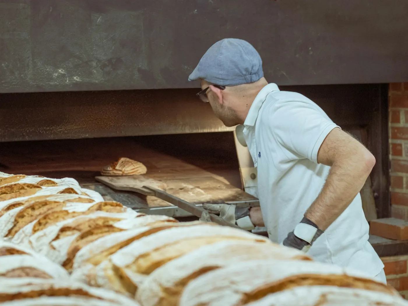 Fornaio che sforna il pane dal forno a legna